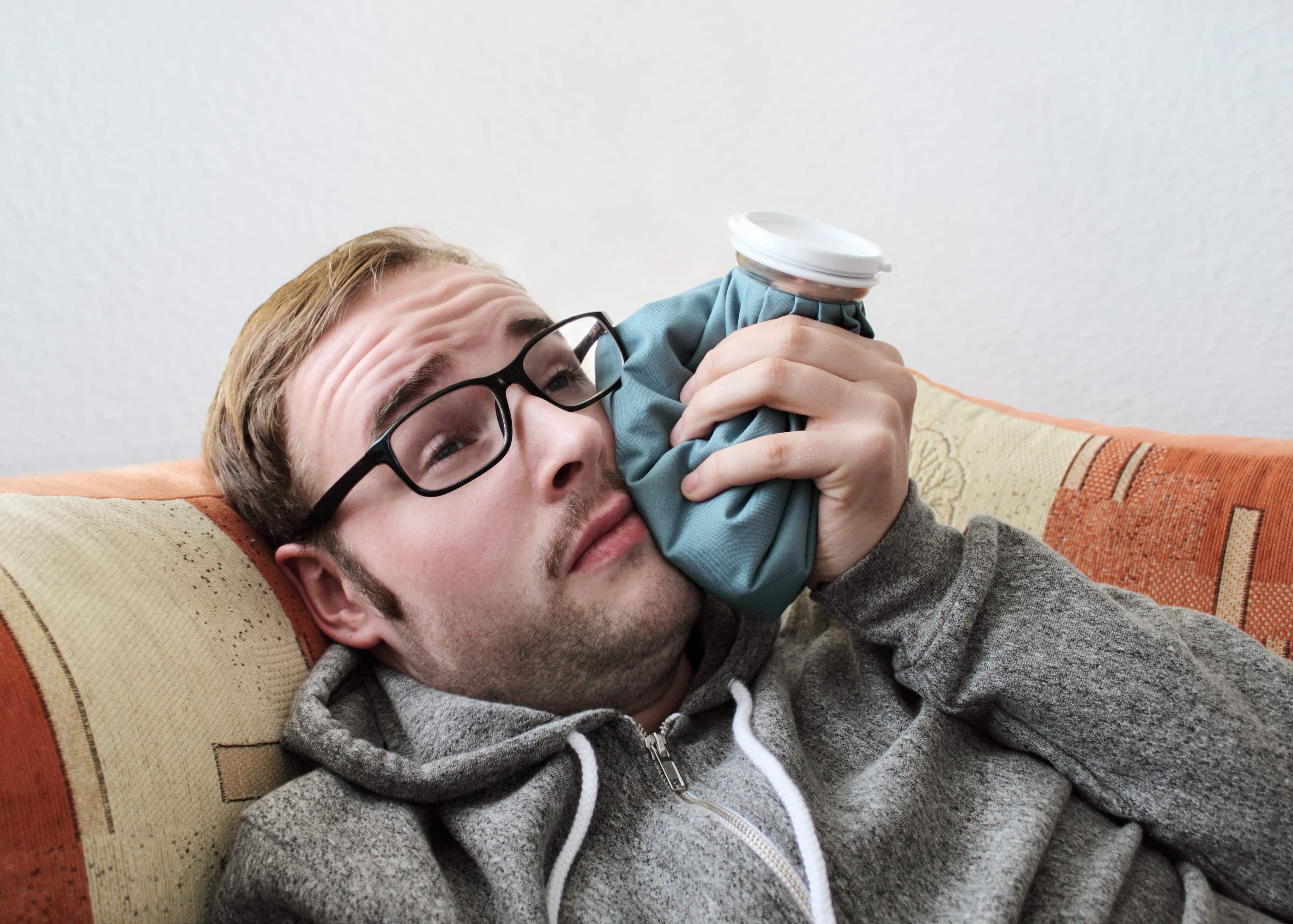 man putting ice on tooth after wisdom tooth removal