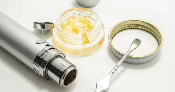 image showing a dab vape pen, dab in a container, anda dabbing tool